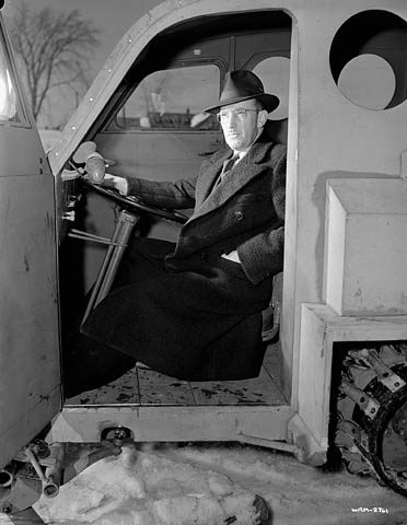 Black and white photograph of Joseph-Armand Bombardier seated in the driver's seat of a vehicle